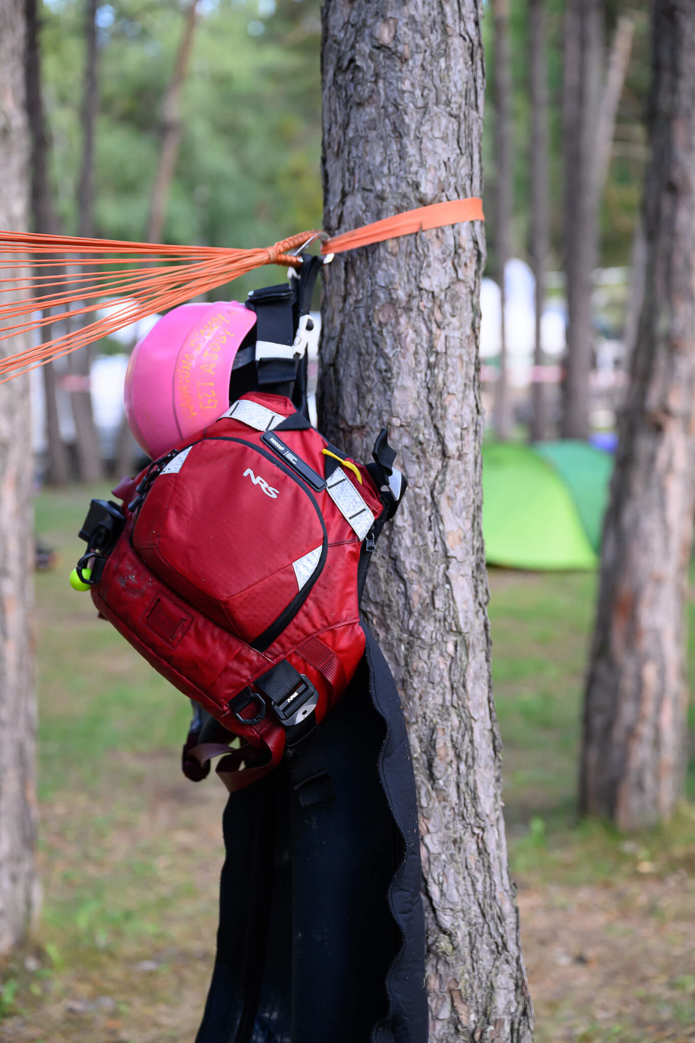 ubayak-06-camp-gear-drying-by-cedric-eyma Buoyancy aid and helmet hung on a pine to dry, the hammock strap tied to the trunk.